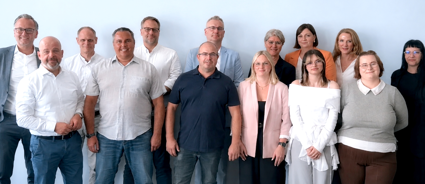 Das EGV-Teamfoto. In zwei Reihen stehen die Mitarbeiter der EGV vor einer weißen Wand in einem Büro und blicken in die Kamera.