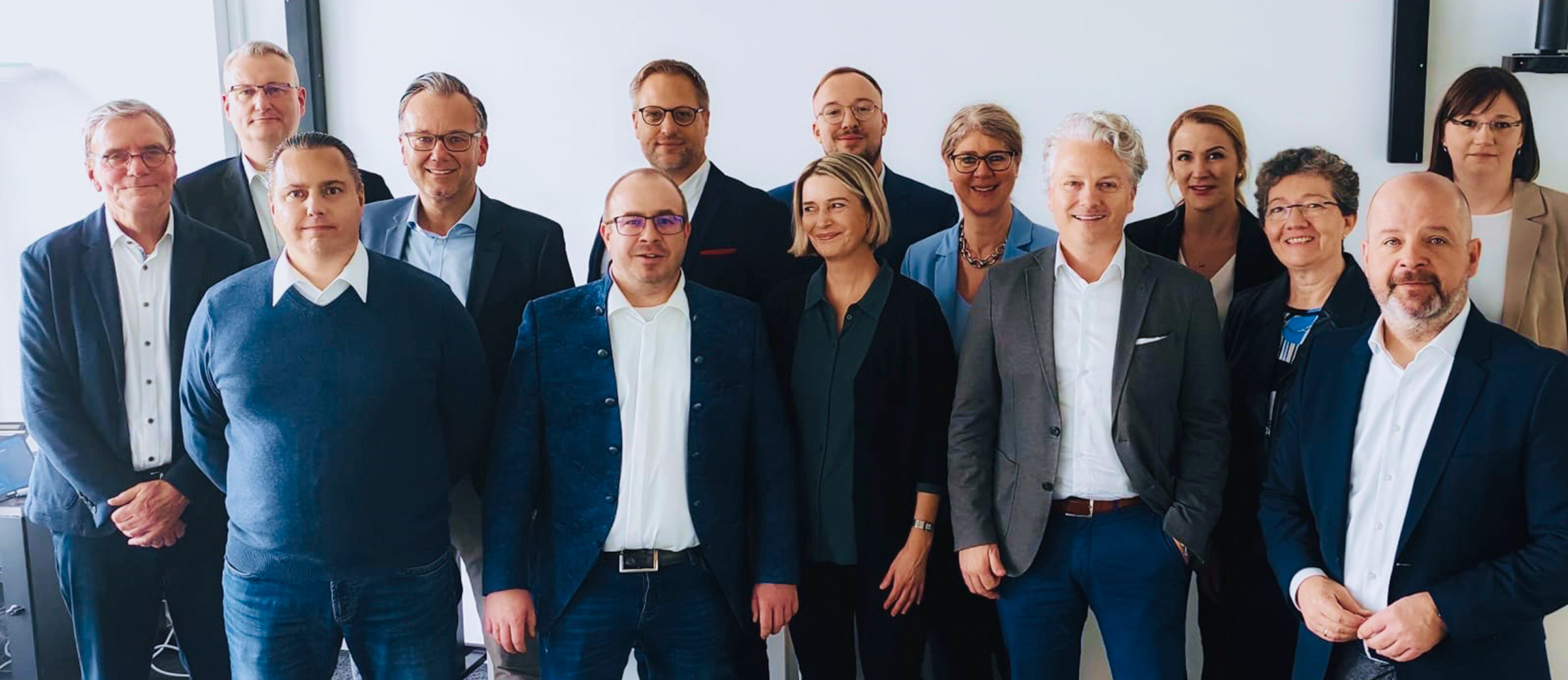 Das EGV-Teamfoto. In zwei Reihen stehen die Mitarbeiter der EGV vor einer weißen Wand in einem Büro und blicken in die Kamera.